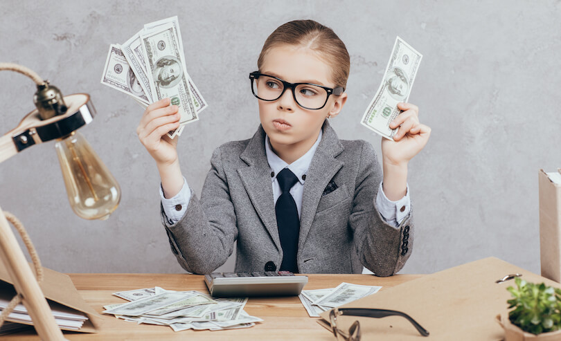 Petite fille avec des lunettes, une calculatrice et des billets de banque